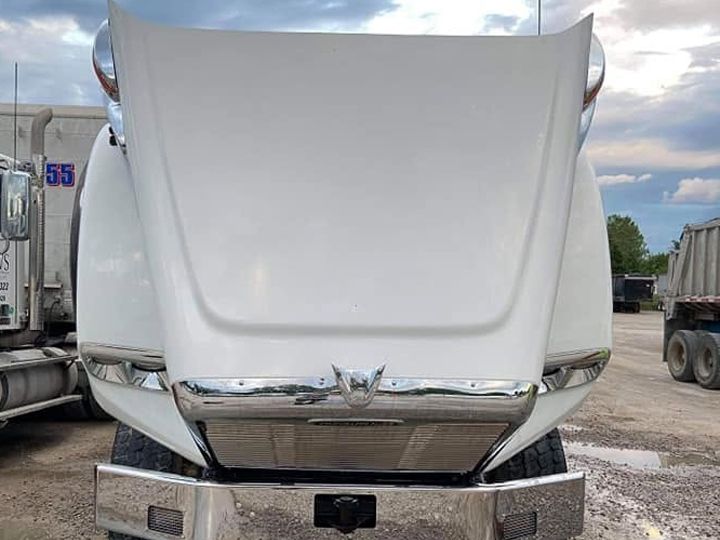 White truck hood raised, now bright white and clean under a cloudy evening sky.